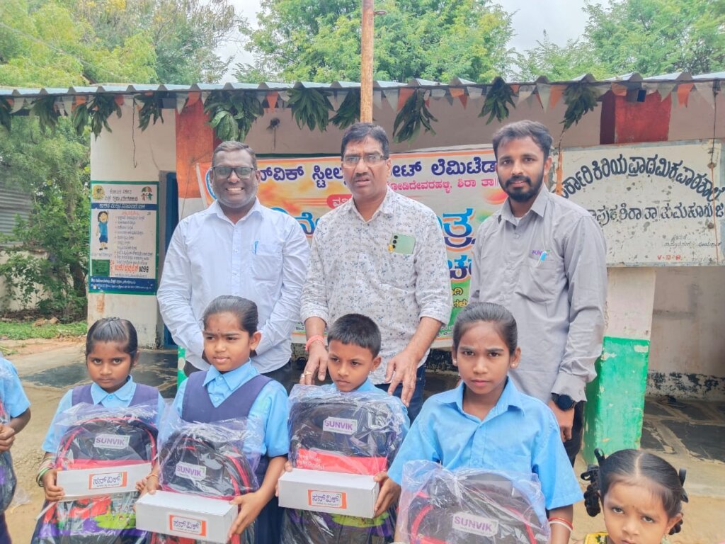 Sunvik Steels team with government school students holding new school bags and kits